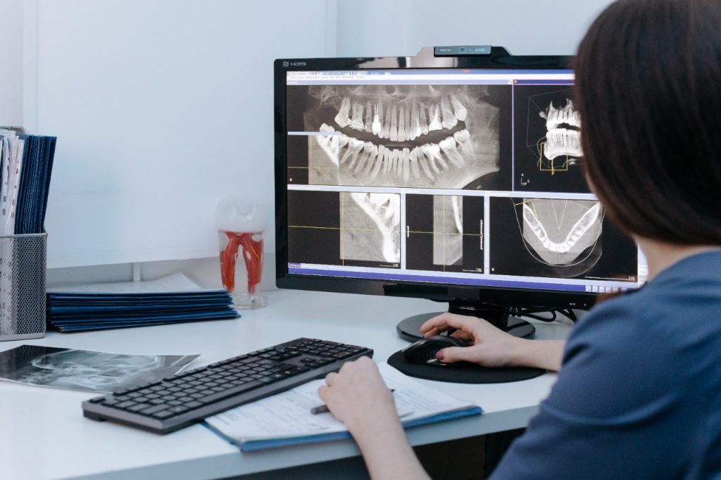 A woman is using a computer for dental diagnostics.